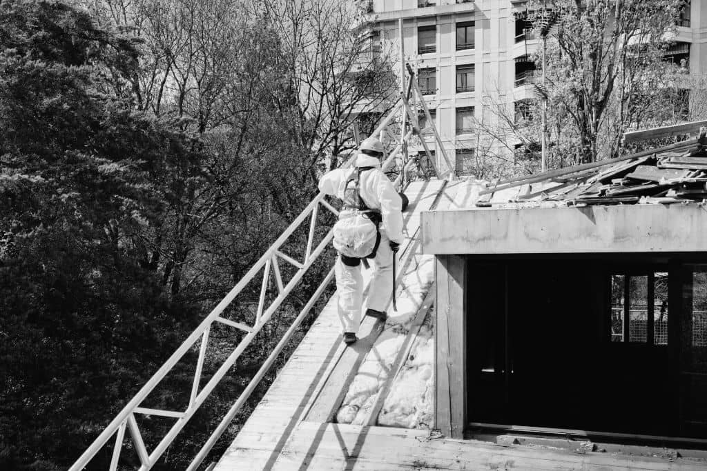 article prix désamiantage toit - un ouvrier réalise des travaux de désamiantage sur le toit d'une maison